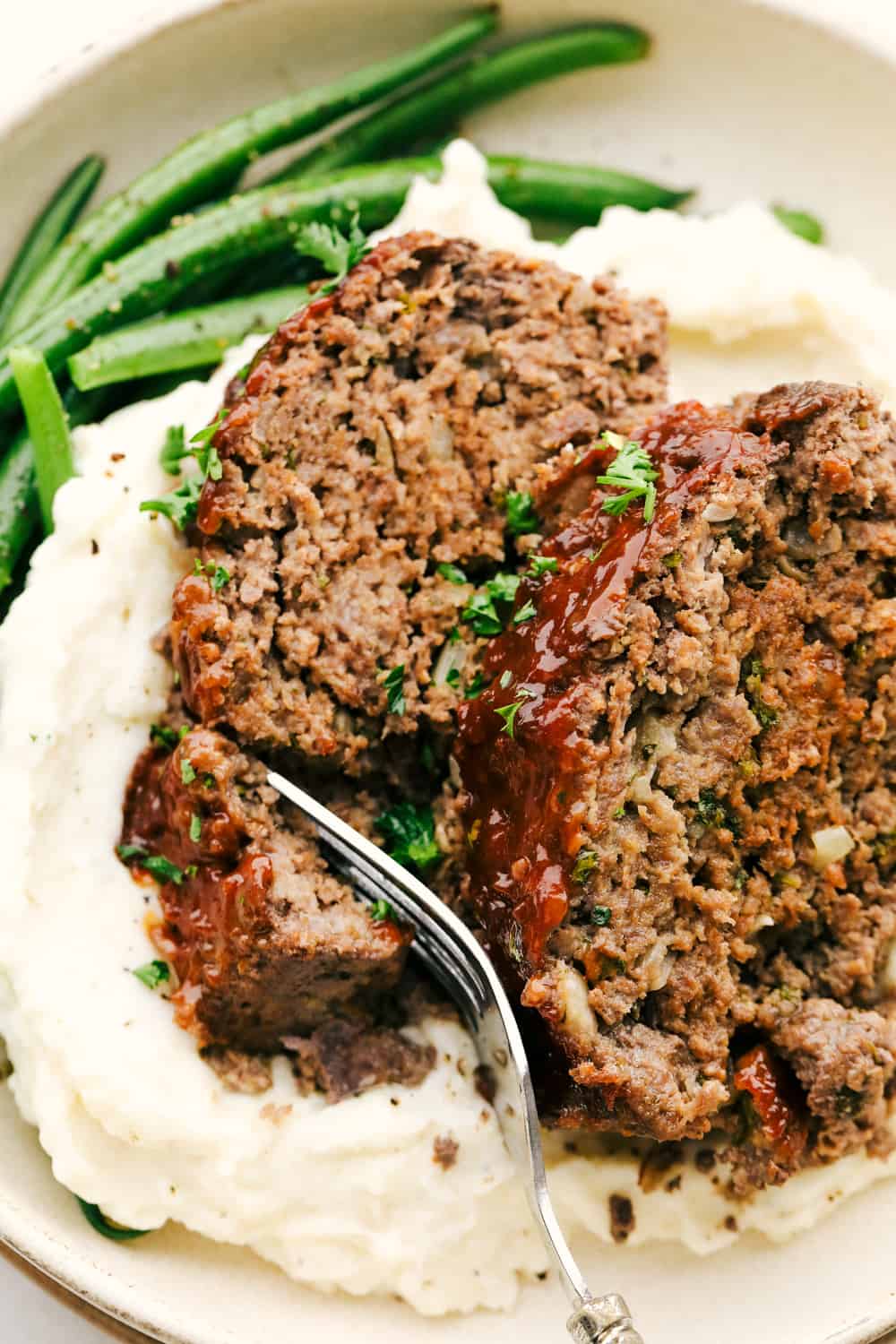 Hearty foolproof meatloaf on a bed of mashed potatoes and beans.